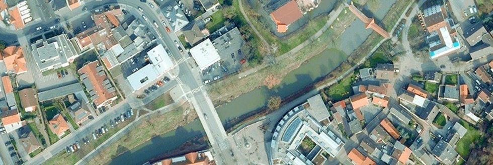 Luftaufnahme eines Flusses mit Brücke und umliegenden Gebäuden in einer Stadt