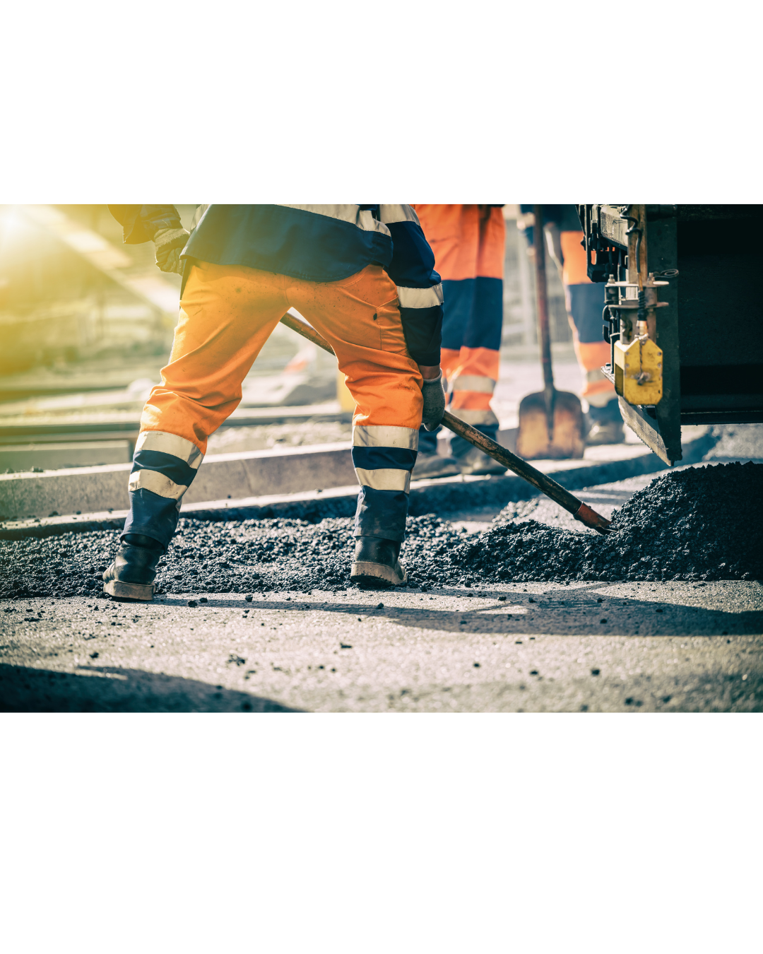Beine von Bauarbeitern in Warnkleidung beim Verteilen von frischem Asphalt auf einer Straße