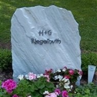 Grabstein umgeben von bunten Blumen auf einem Friedhof