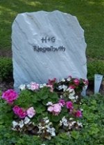 Grabstein umgeben von bunten Blumen auf einem Friedhof