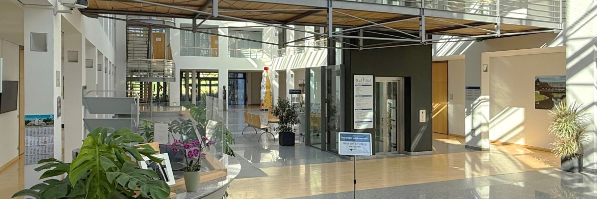 Rathausfoyer Heller, moderner Rathausfoyer mit Glasdach, Pflanzen, Sitzbänken und einem Aufzug in der Mitte