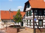 Fachwerkhaus mit rotem Ziegeldach und kleinem Baum vor einem Backsteinmauerabschnitt in Bad Vilbel Massenheim