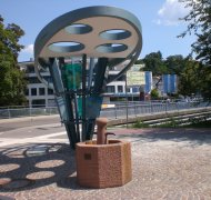 Brunnen an der Rathausbrücke Moderner Brunnen mit sechseckigem Becken aus Stein auf gepflastertem Platz neben einer Straße mit Brücke und Gebäuden im Hintergrund