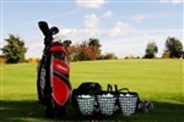 Golfplatz mit Golftasche und zwei Körben voller Golfbälle auf Gras unter blauem Himmel