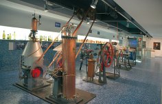 Museumsausstellung mit historischen Destillationsapparaten aus Kupfer und Metall in einer modernen, hellen Halle