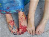 Nahaufnahme von zwei nackten Füßen, von denen ein Paar mit roter Farbe bedeckt ist