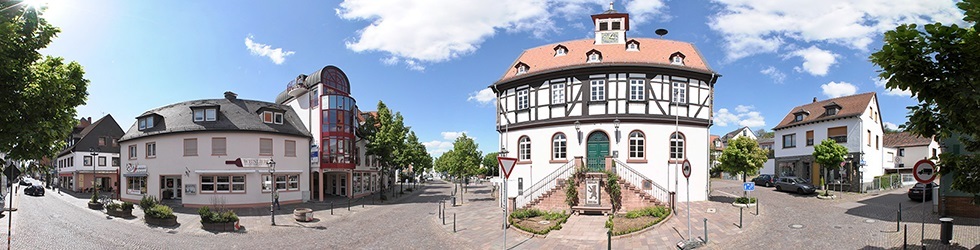 Panoramablick auf einen historischen Fachwerkbau mit Treppe und umliegende Wohnhäuser an einem sonnigen Tag