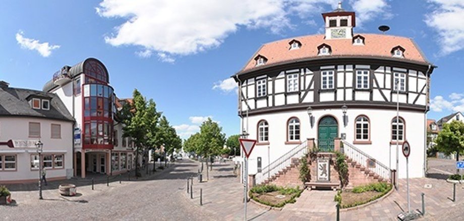 Panoramablick auf einen historischen Fachwerkbau mit Treppe und umliegende Wohnhäuser an einem sonnigen Tag