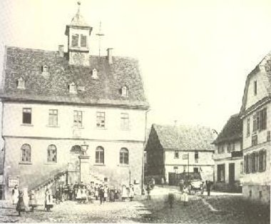 Schwarz-weiße Aufnahme des historischen Rathauses Bad Vilbel mit einer Gruppe von Menschen davor