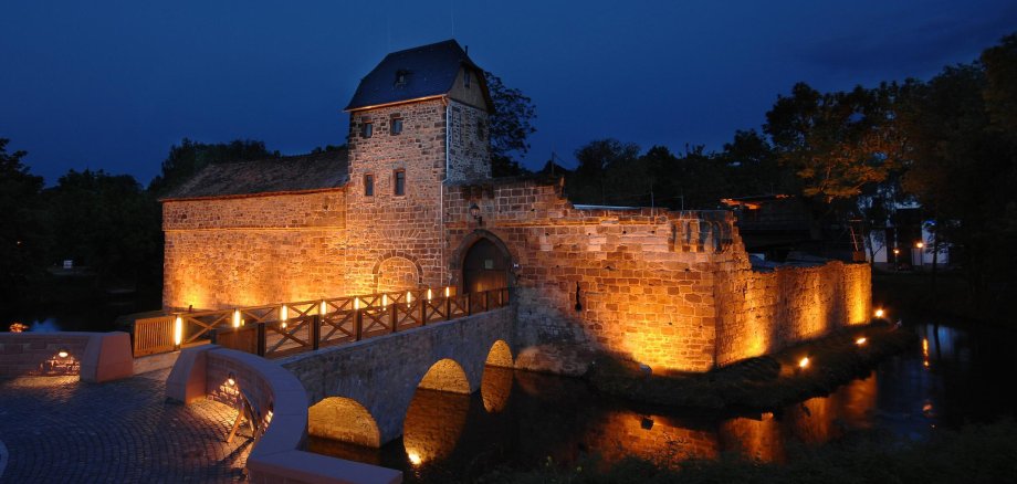 Wasserburg Bad Vilbel Beleuchtete mittelalterliche Wasserburg bei Nacht unter klarem Himmel mit sichtbarem Vollmond
