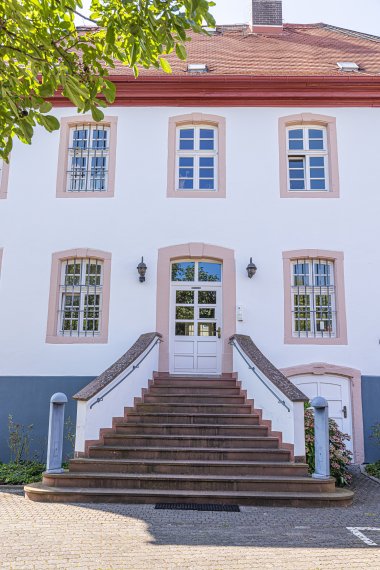 Treppenaufgang mit symmetrischen Fenstern und weißer Fassade eines zweistöckigen Hauses