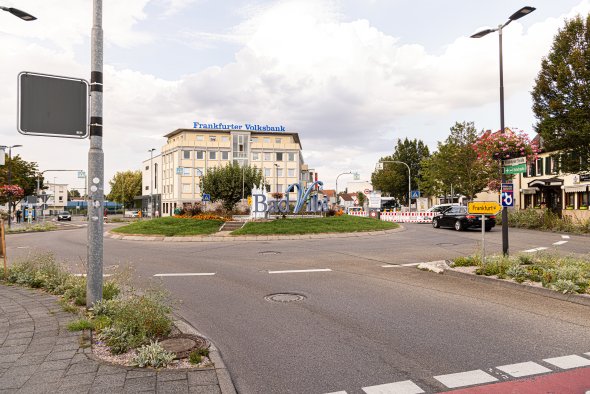 Kreisverkehr mit Blumenbeeten und Schriftzug Bad Vilbel vor einem Gebäude der Frankfurter Volksbank