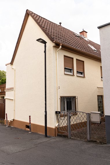 Einfamilienhaus mit Satteldach, zwei geschlossenen Rollläden an Fenstern und einem Metalltor vor dem Eingang