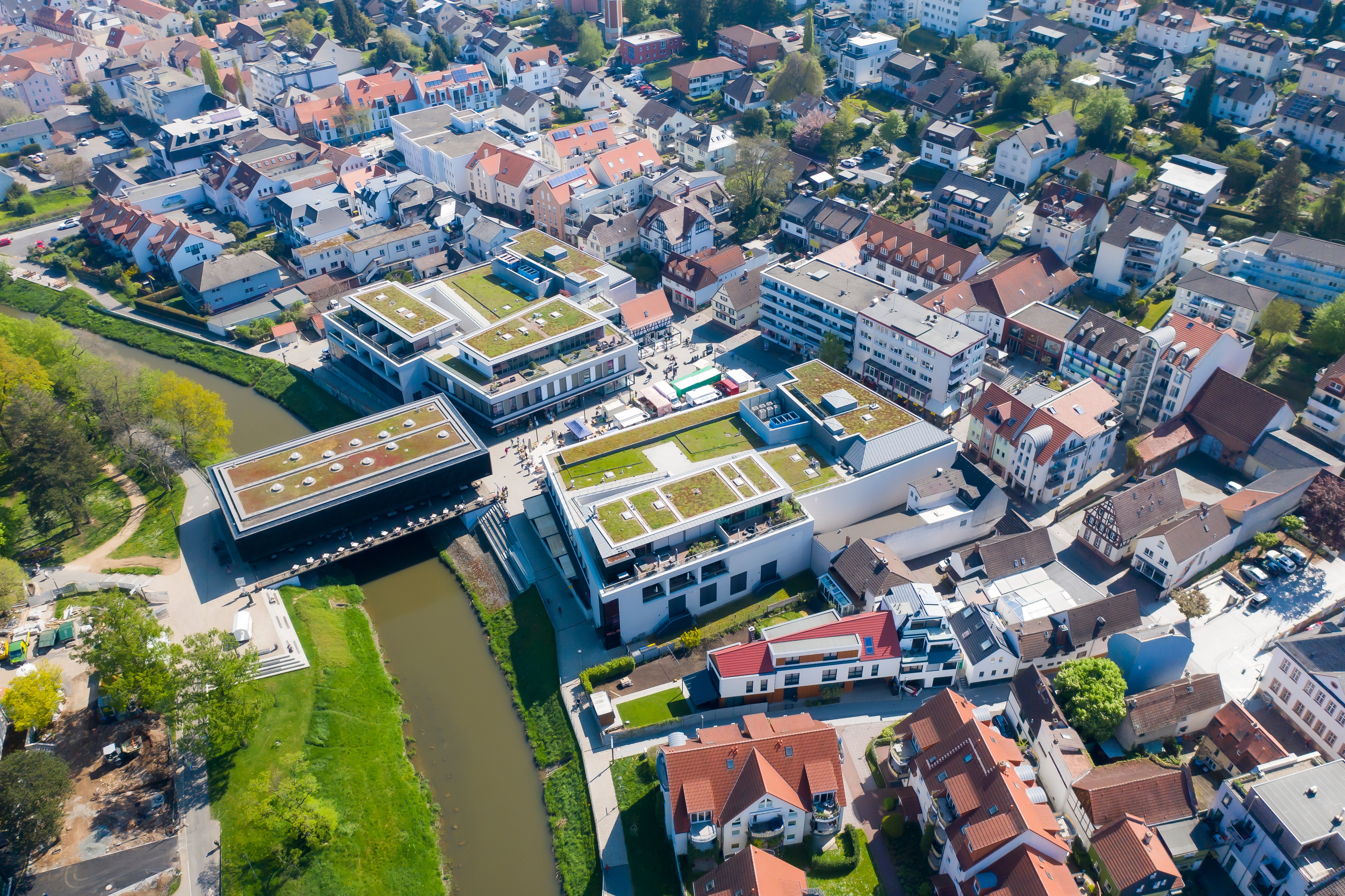 Luftaufnahme von Bad Vilbel mit Fluss, modernen Gebäuden mit begrünten Dächern und dicht bebauten Wohnhäusern