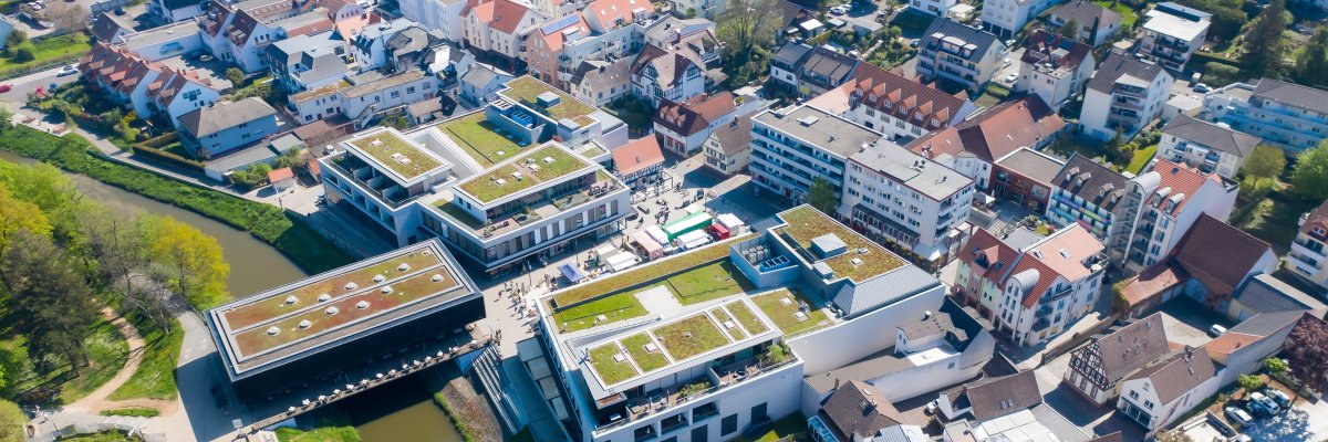Luftaufnahme Bad Vilbel Luftaufnahme von Bad Vilbel mit Fluss, modernen Gebäuden mit begrünten Dächern und dicht bebauten Wohnhäusern