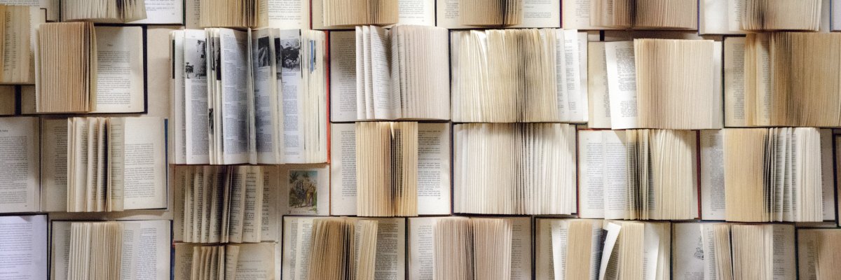 Mehrere aufgeschlagene Bücher liegen eng nebeneinander mit sichtbaren Textseiten