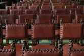 Reihe von braunen Lederstühlen mit Nieten und geschnitzten Holzarmlehnen in einem Saal
