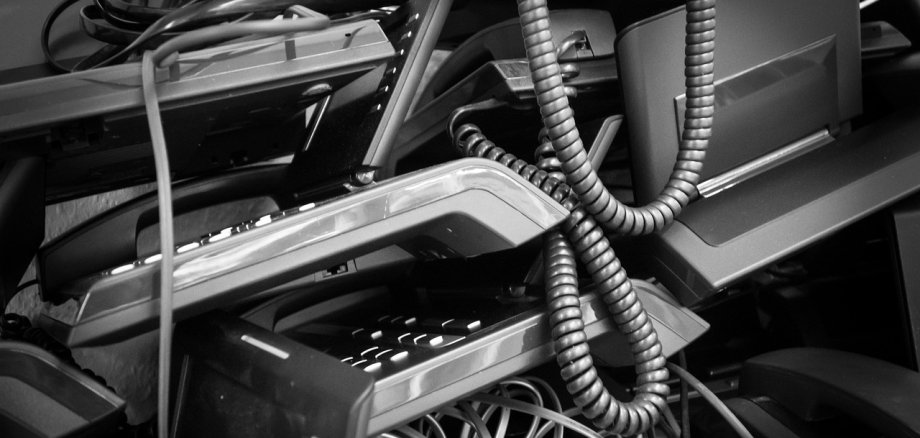 Schwarz-weiße Nahaufnahme von einem Haufen Elektroschrott mit Kabeln und alten elektronischen Geräten