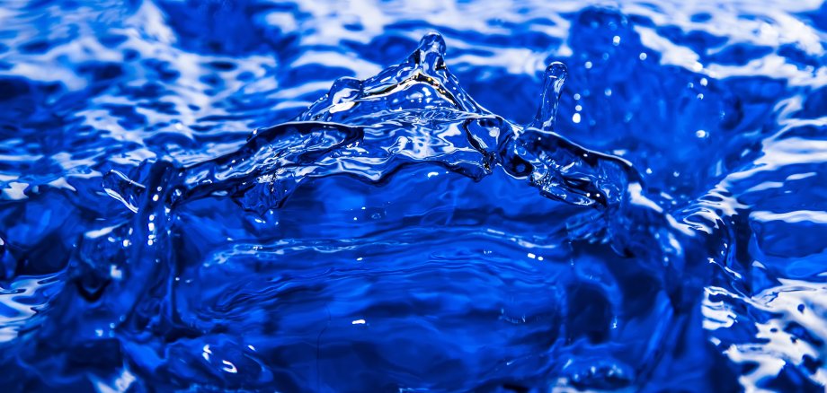 Nahaufnahme von Wasser, das eine Welle mit Tropfen bildet