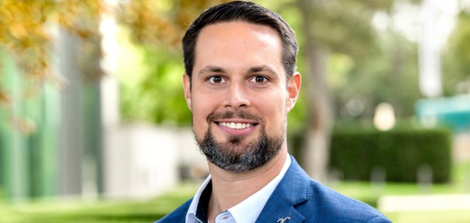 Porträt Erster Stadtrat Bastian Zander Porträt des ersten Stadtrats aus Bad Vilbel Bastian Zander. Ein Mann mit dunklem Haar und Bart, trägt weißen Hemdkragen und blauen Anzug vor unscharf grünem Hintergrund