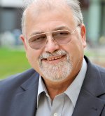 Älterer Mann (Ehrenstadtverordneter Klaus Althoff) mit Brille, grauem Bart und Anzugjacke lächelt in die Kamera