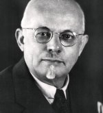 Porträt eines älteren Mannes (ehrenbürgermeister Kurt Moosdorf) mit Brille, Glatze und Spitzbart, der einen Anzug mit Krawatte trägt